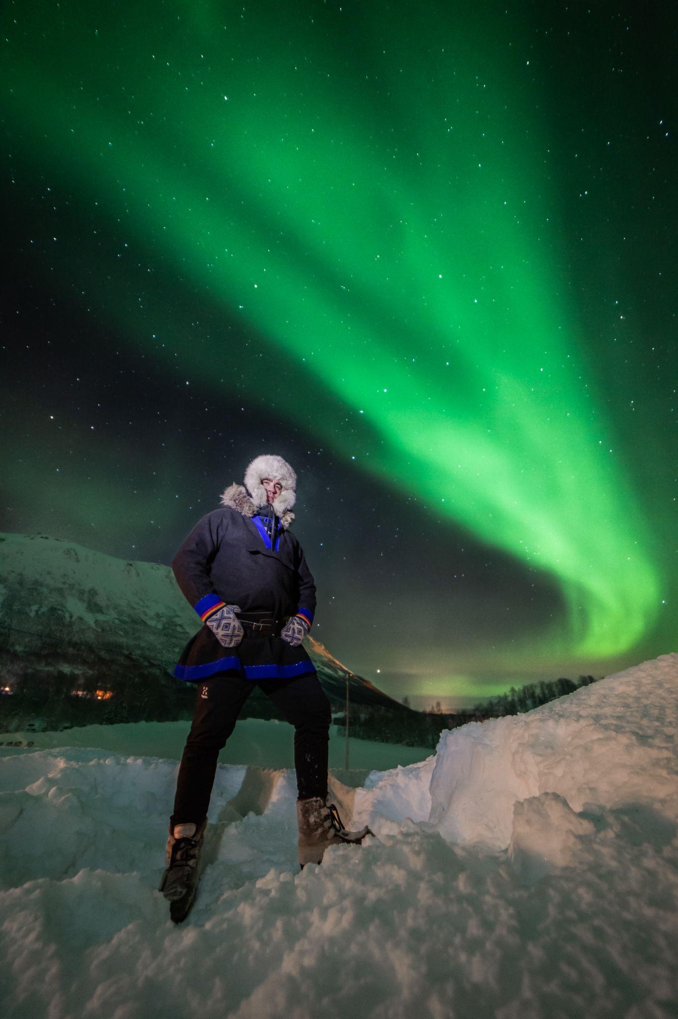 Odd Levi standing in the snow under a green aurora